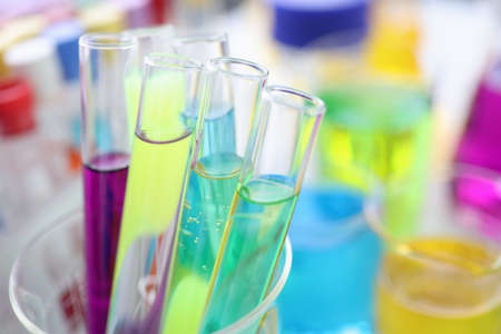 Chemical test tubes with multi-colored liquid on desktop in laboratory