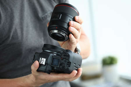 Male hands putting on modern digital camera professional lensの写真素材