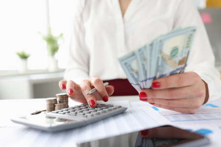 Woman holds American banknotes in her hands and works on calculatorの写真素材