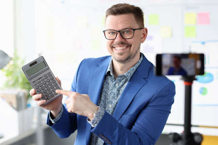 Smiling businessman blogger holding calculator in his handsの写真素材