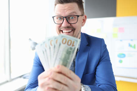 Joyful businessman holds cash in his handsの写真素材