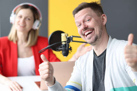 Joyful man and woman are working on air of radio stationの写真素材