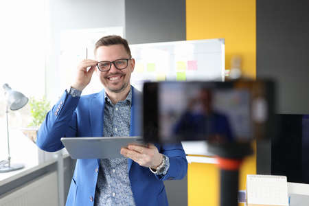 Young business coach smiling and adjusting glasses at mobile phone cameraの写真素材