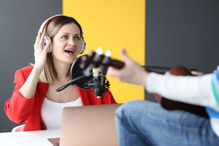 Woman and man in headphones singing and playing guitar