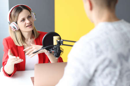 Young woman with headphones interviewing man on radioの写真素材