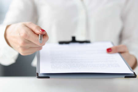 Business woman giving document on clipboard for signature closeupの写真素材