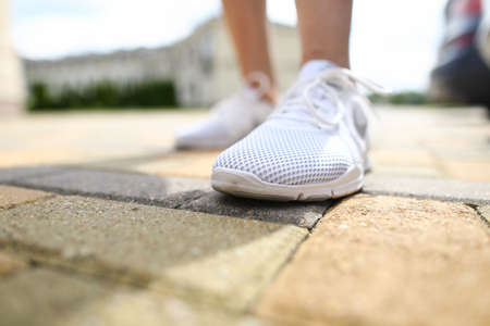 Close-up of person wearing shiny white sneakersの写真素材