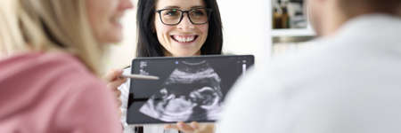 Doctor demonstrates childs ultrasound to couple closeupの写真素材