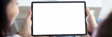Woman and man are sitting on couch at home and holding tablet in their hands closeup