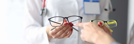 Ophthalmologist shows patient two pairs of optics.の写真素材