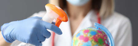 Doctor is holding globe and disinfectant closeupの写真素材