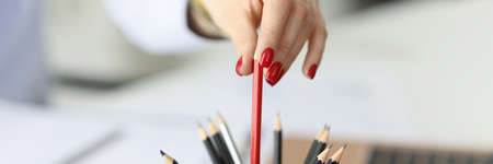 Female hand with red nails holds red pencil.の写真素材