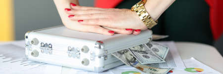 Female hands closing suitcase with money in office closeup