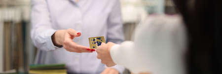 Customer handing credit bank card to sellers hand closeupの写真素材