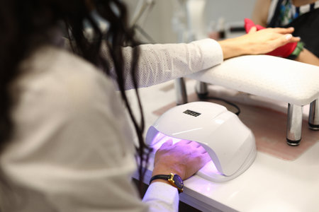 Close-up of woman putting finger under uv lamp. Gel nail polishの写真素材