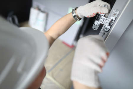 Close-up of carpenter installing wooden door hingesの写真素材
