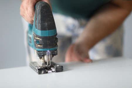 Close-up of qualified worker using electrical instrument for work with wood