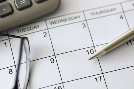 Close-up of calendar and glasses laying on working table