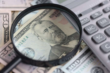 On the table are American billsv magnifying glass and calculator.の写真素材