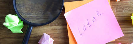 Crumpled multicolored pieces of paper and magnifying glass lying on tableの写真素材