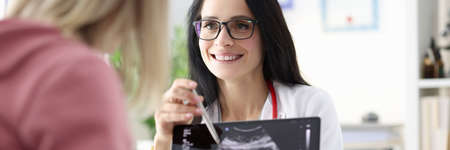 Gynecologist showing patient ultrasound of fetus on tablet