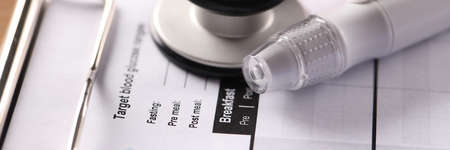 Lancet and blood glucose meter lying on clipboard with medical documents closeupの写真素材