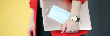 Business woman holding laptop and medical protective mask