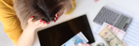 Young woman holding her head in front of cashの写真素材