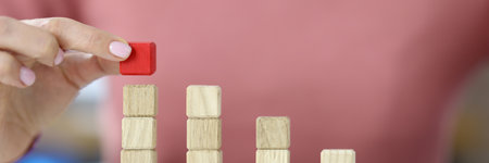 Female hand drawing graph from wooden toy cubesの写真素材