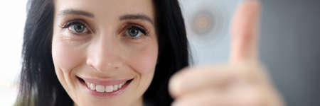 Smiling woman holds her thumbs up closeup