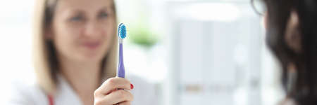 Dentist shows patient toothbrush. How to choose the right toothbrushの写真素材