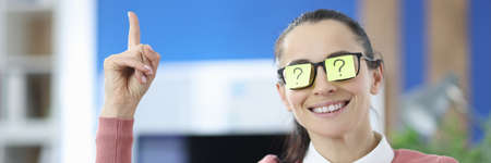 Woman has colored sticker with question mark on her glasses and holds her thumbs upの写真素材