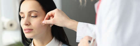 Doctor sticking adhesive plaster on patients faceの写真素材