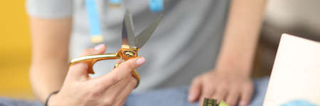 Female hand holds scissors near thread and fabricの写真素材