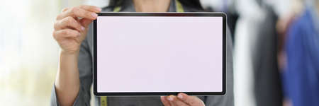 Young woman seamstress holding digital tablet in her hands closeupの写真素材