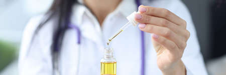 Doctor holds bottle with yellow liquid and pipetteの写真素材