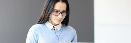 Young woman in headphones looking at laptop screenの写真素材