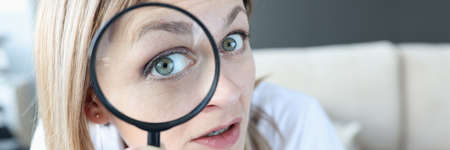 Woman doctor looking through magnifying glass closeup