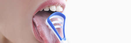 Young woman cleaning her tongue with scraper closeupの写真素材