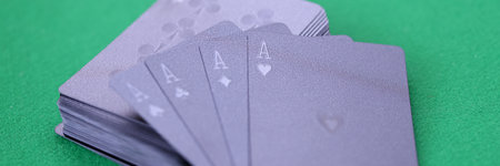 Black playing cards with aces lie on green gaming table