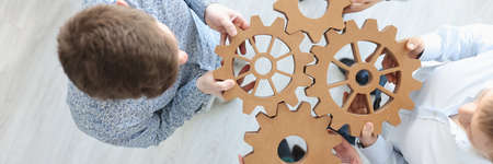 Business people holding wooden gears in office top viewの写真素材