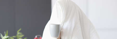 Man sitting under blanket with cup of coffeeの写真素材
