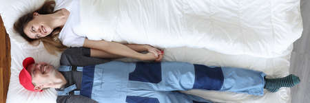 Man plumber and woman lying under blanket top viewの写真素材