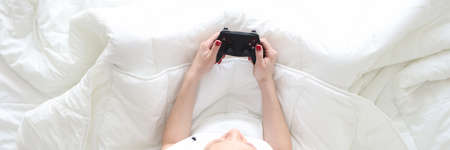 Woman sitting in bed with joystick in her hands top viewの写真素材