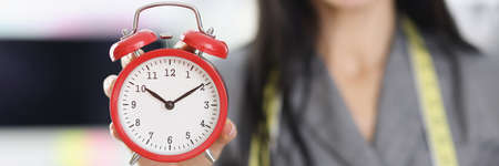 Smiling woman designer stylist holding red alarm clockの写真素材