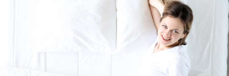 Young woman lying in bed and smiling top view