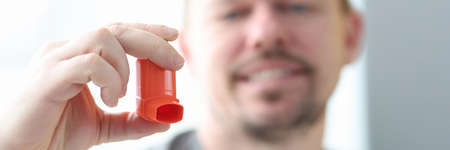 Man holds an inhaler in his hand.