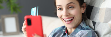 Happy woman holding mobile phone and credit bank cardの写真素材