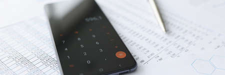 Mobile phone with calculator lying on documents closeupの写真素材