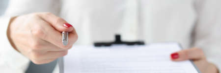 Business woman giving document on clipboard for signature closeupの写真素材